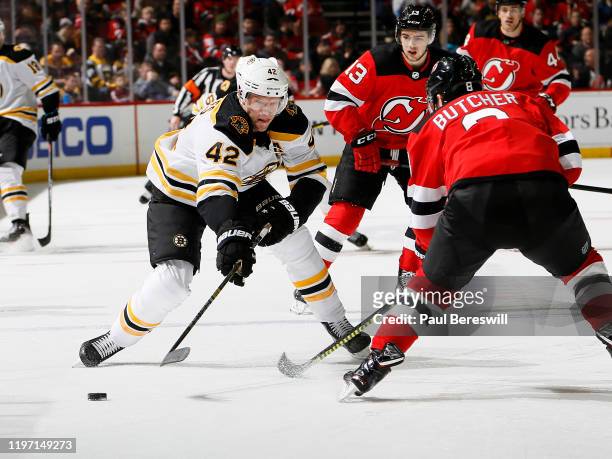 David Backes of the Boston Bruins skates as Nico Hischier and Will Butcher of the New Jersey Devils defend during an NHL hockey game on December 31,...