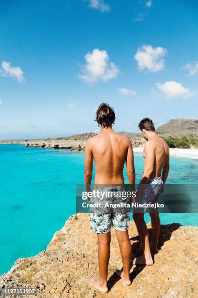 two boys standing at a blue ocean viewpoint the caribbean - bonaire stock pictures, royalty-free photos & images