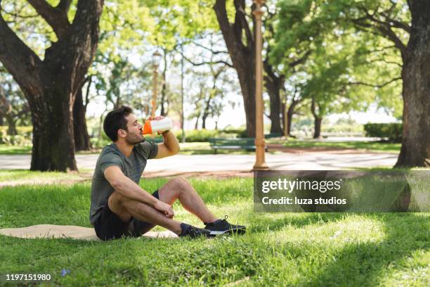 young man drinking a protein shake in the park - healthy eating and exercise stock pictures, royalty-free photos & images