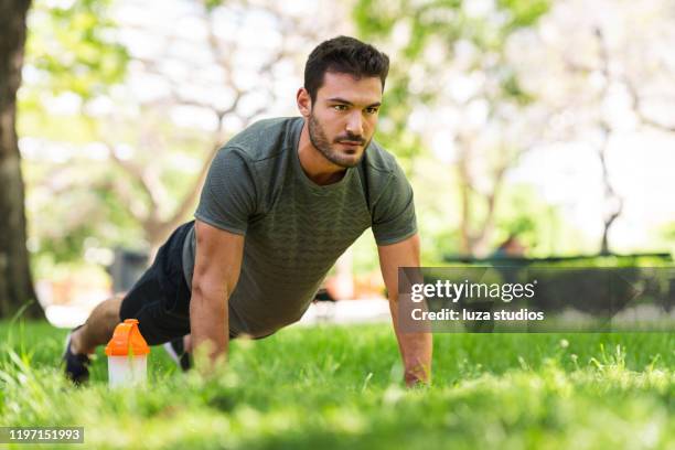 jonge man doet push-up oefeningen in het park - opdrukken stockfoto's en -beelden