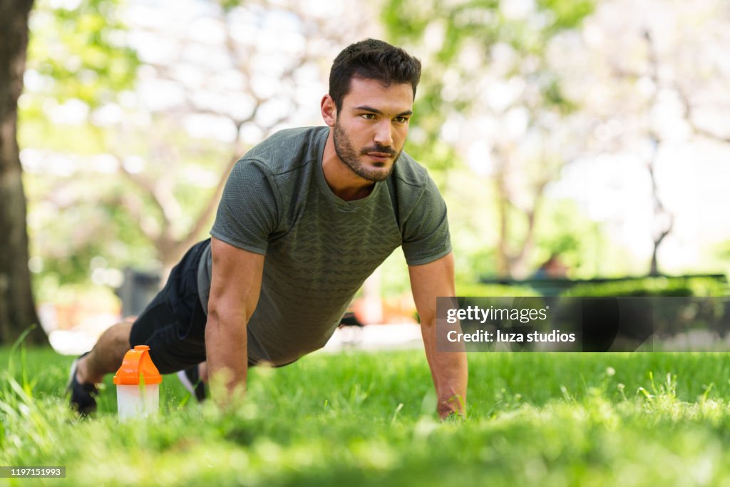 Young man doing push-up exercises in the park