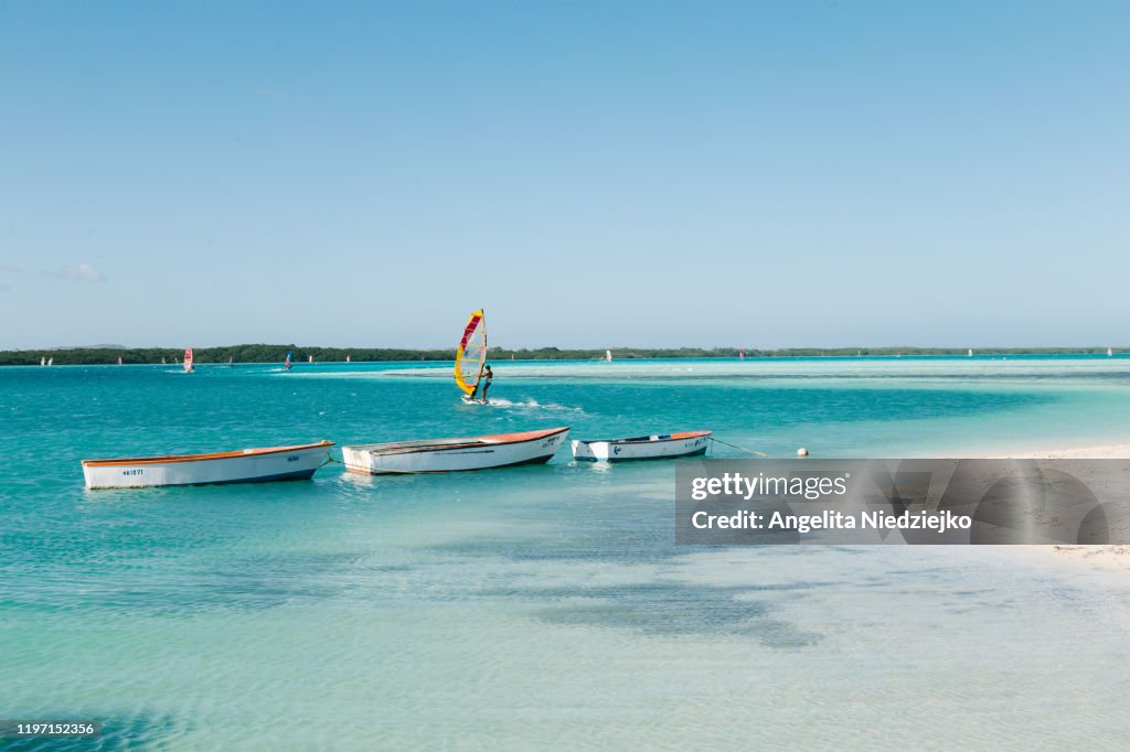 Surfers and boats in the shallow blue waters of Lac Bay, Bonaire Island