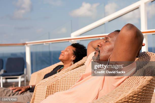 couple on chairs on deck of cruise ship - hands behind head stock pictures, royalty-free photos & images