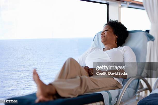 woman reclining on lounge chair on cruise ship - zurücklehnen stock-fotos und bilder