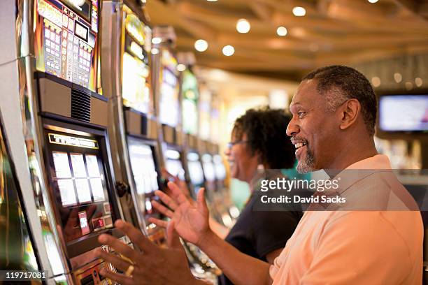 man and woman on slot machine - casino stock pictures, royalty-free photos & images