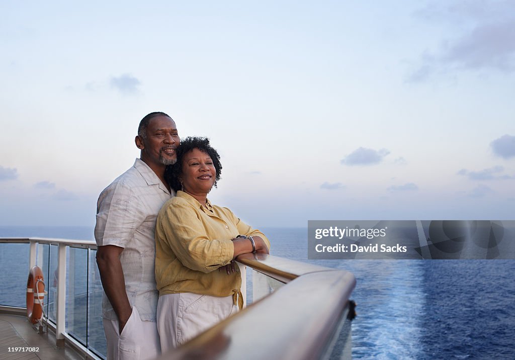 Couple on deck with cruise ship wake behind them