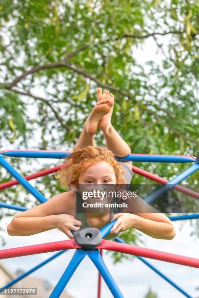 girl upside down on jungle gym smiling at camera - barefoot girl stock pictures, royalty-free photos & images