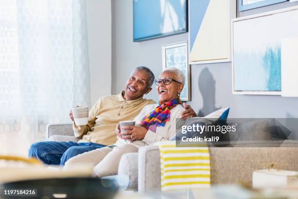 senior african-american couple at home watching tv - african american watching tv stock pictures, royalty-free photos & images