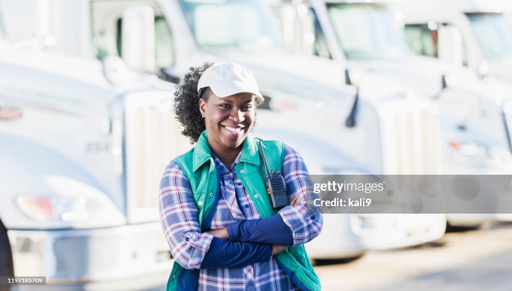 African-American woman standing in front of semi-trucks