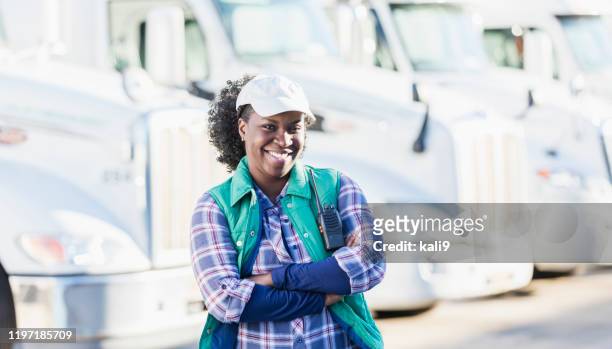 african-american woman standing in front of semi-trucks - fleet of vehicles stock pictures, royalty-free photos & images
