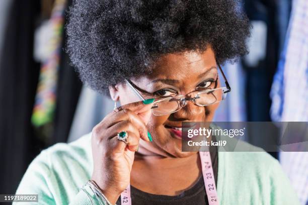 woman working in clothing store peering over glasses - peeking over stock pictures, royalty-free photos & images