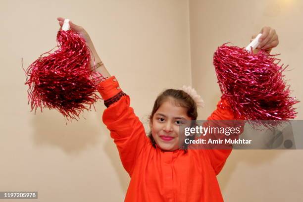 a young cute girl practicing with her pom-pom (prop) indoor and looking at camera - pom pom stock-fotos und bilder