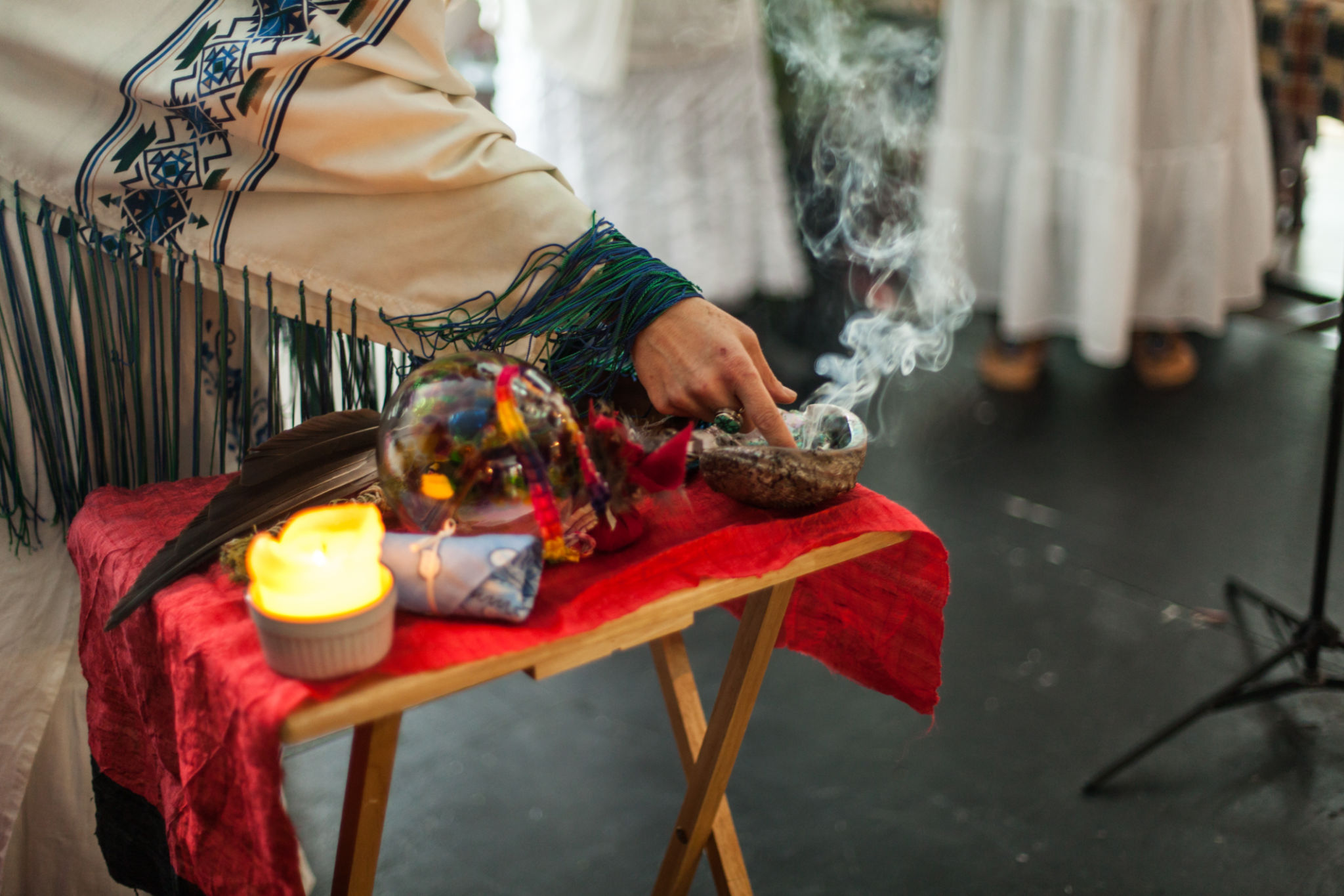 Woman in ceremonial robe is touching smoking sage Woman in ceremonial robe is touching smoking sage