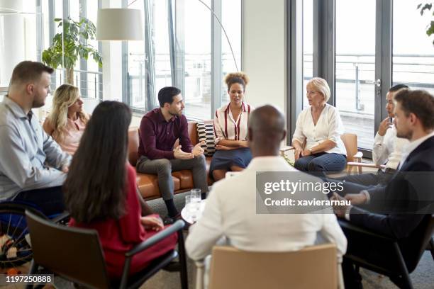 44relaxed group of businesspeople conversing in lobby - mixed age range stock pictures, royalty-free photos & images