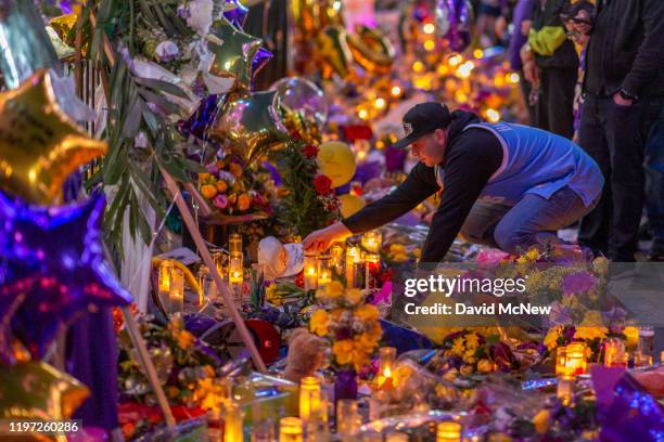 Man places a hat at a makeshift memorial near Staples Center in remembrance of former NBA great Kobe Bryant who, along with his 13-year-old daughter...