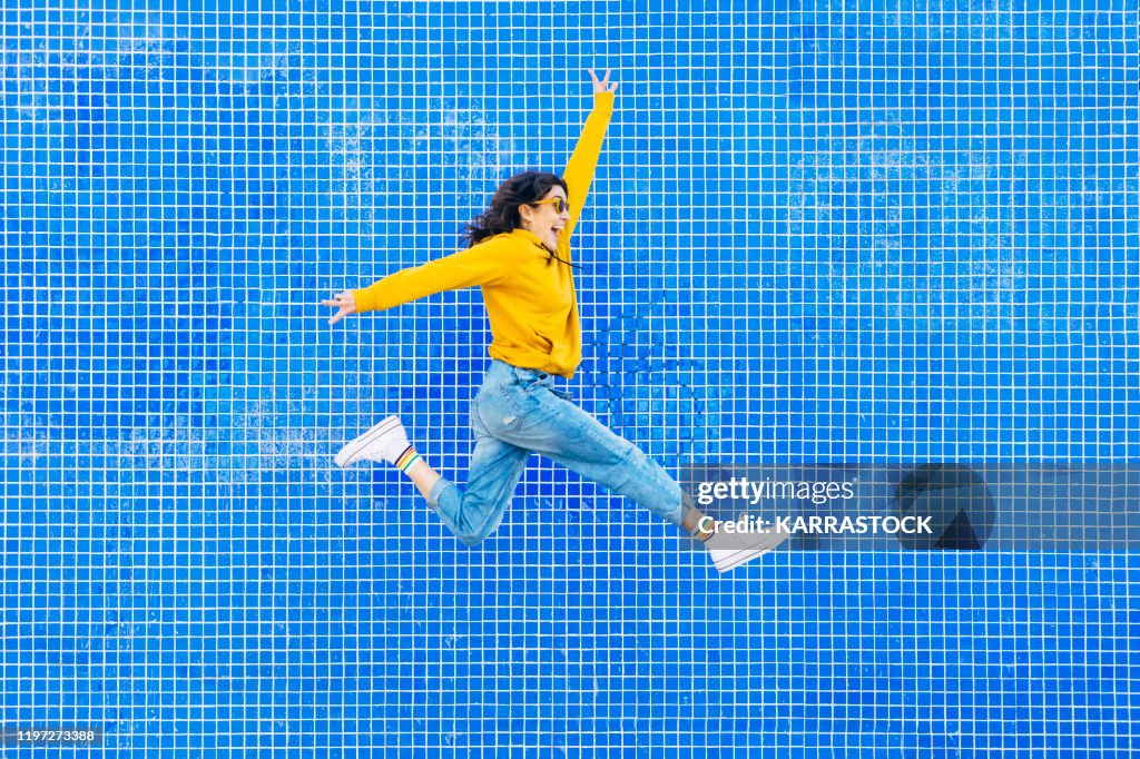 Woman jumping in front of a blue background