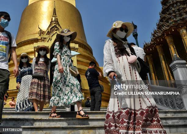 Tourists wearing face masks visit the Grand Palace in Bangkok on January 29, 2020. - Thailand has detected 14 cases so far of the novel coronavirus,...