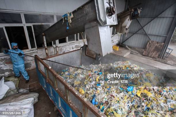 This photo taken on January 28, 2020 shows a staff member wearing protective clothing disposing of medical waste at a medical waste treatment plant...