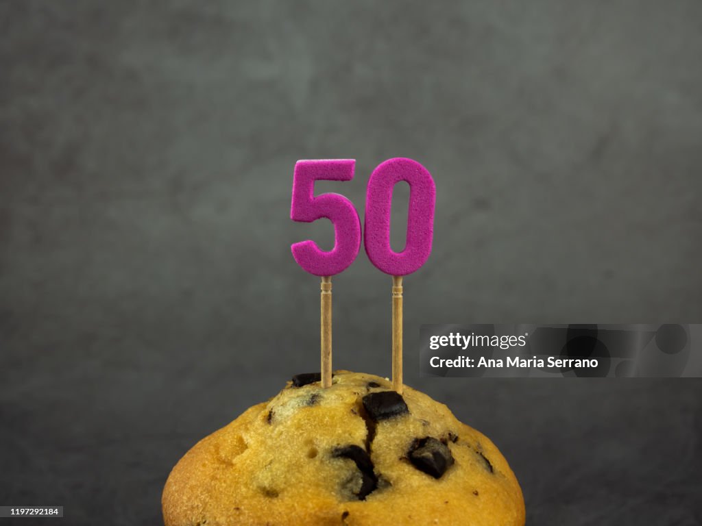 50th Birthday candles in a cupcake with chocolate pieces on a dark background