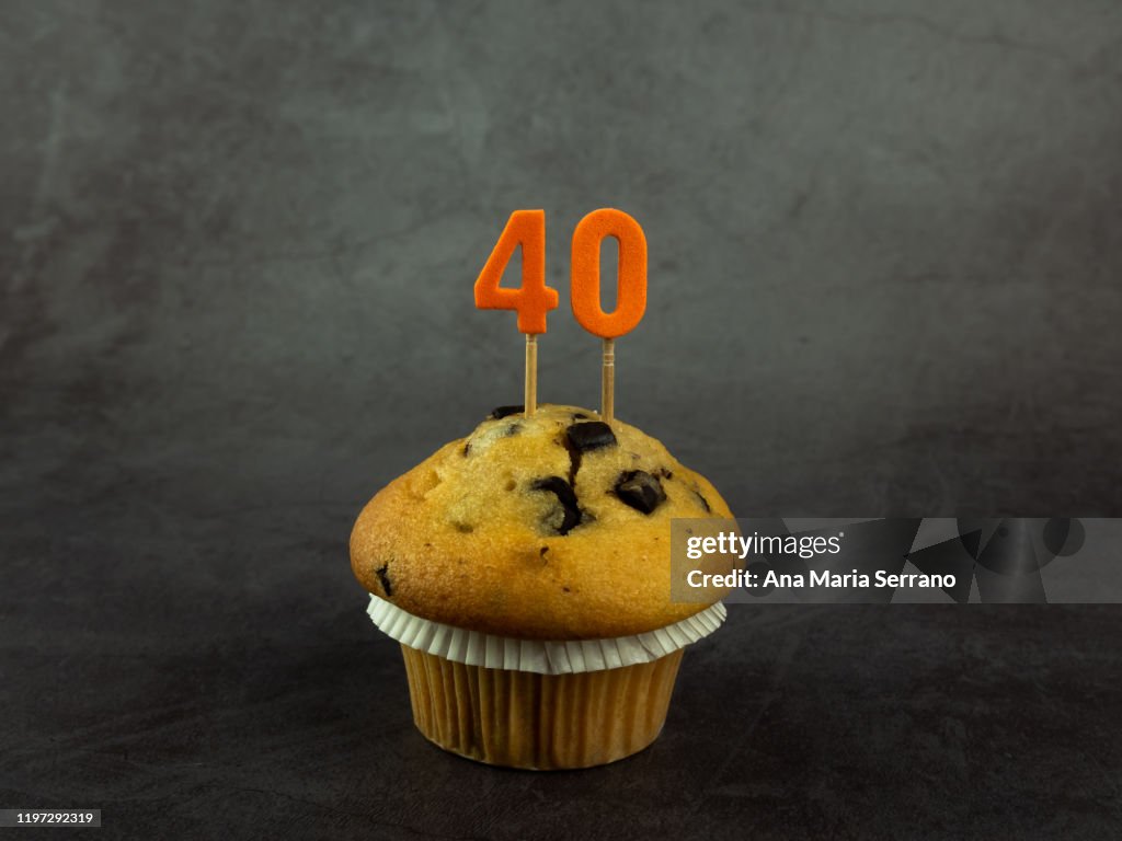 40th Birthday candles in a cupcake with chocolate pieces on a dark background