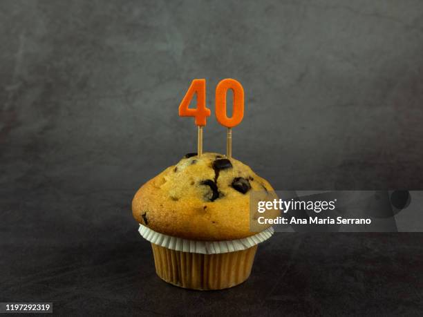 40th birthday candles in a cupcake with chocolate pieces on a dark background - 40th birthday stock pictures, royalty-free photos & images