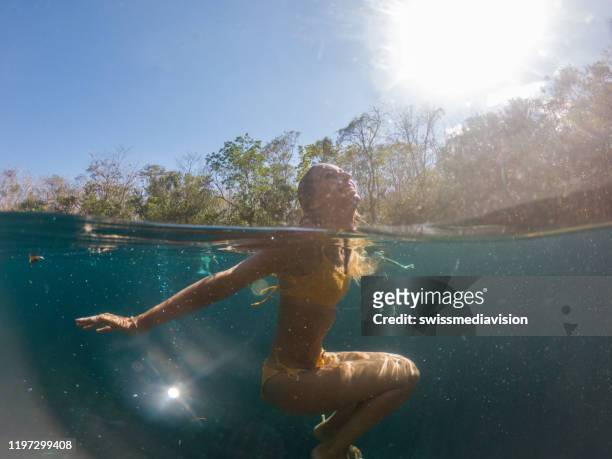 spaccata foto subacquea di donna in cenote messicano - half underwater foto e immagini stock
