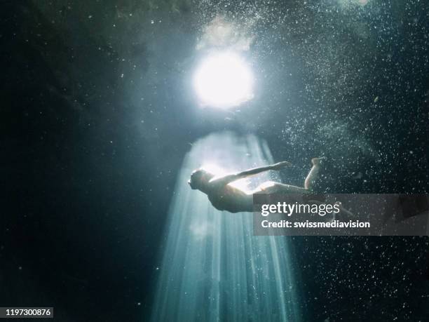 underwater shot of woman diving in mexican cenote - underwater sunlight stock pictures, royalty-free photos & images