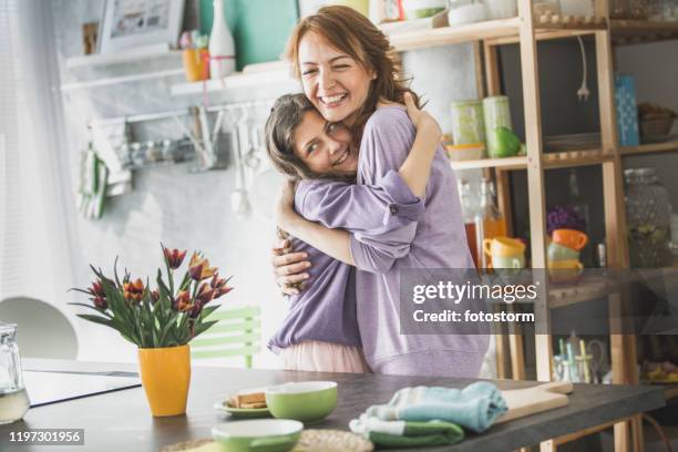 mom and daughter hugging in the kitchen - mother congratulating stock pictures, royalty-free photos & images