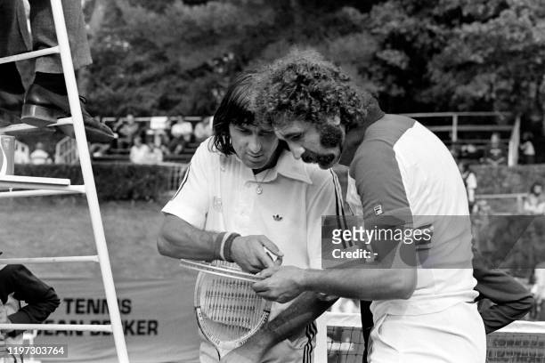 Le tennisman roumain Ilie Nastase et son compatriote Ion Tiriac observent la raquette à double cordage, le 28 septembre 1977, au cours de la 3ème...