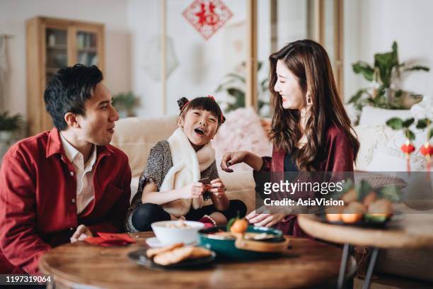 lovely daughter chatting joyfully with father and mother and enjoying family bonding time while celebrating chinese new year at home - chinese family eating stock pictures, royalty-free photos & images