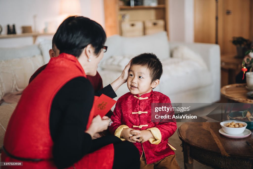 可愛的小孫子身著紅色傳統中國服裝問候祖父母，並在中國農曆新年快樂地收到紅色信封（萊看）