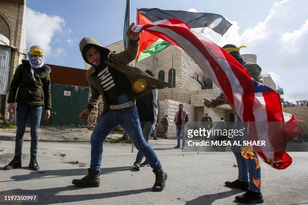 Palestinian demonstrator waves a burning US flag during clashes with Israeli security forces following a protest in the West Bank city of Bethlehem,...