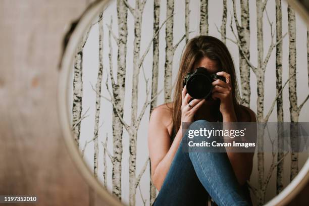 woman holding camera taking photo of her reflection in the mirror. - self portrait stock pictures, royalty-free photos & images