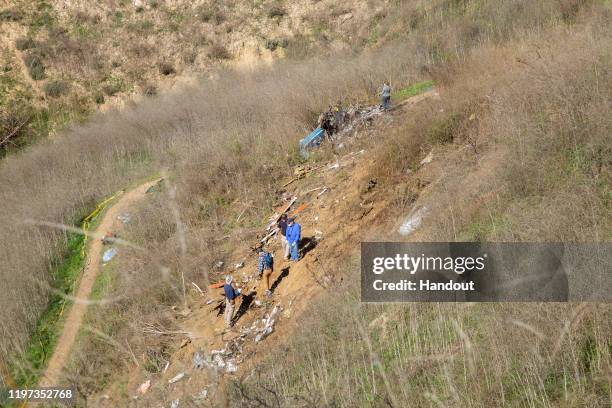 In this handout photo provided by the National Transportation Safety Board, investigators work at the scene of the helicopter crash that killed...