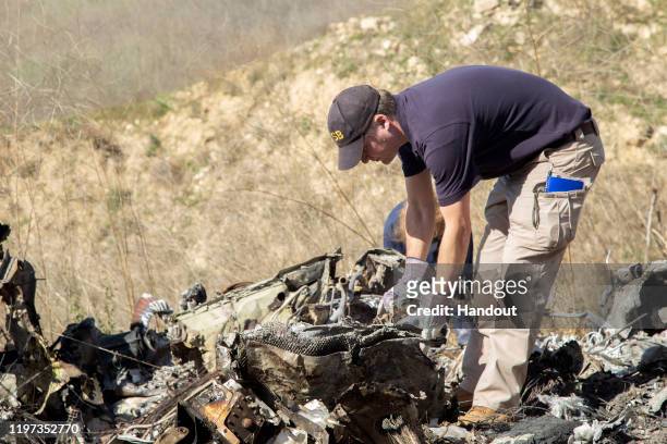 In this handout photo provided by the National Transportation Safety Board, investigators work at the scene of the helicopter crash that killed...