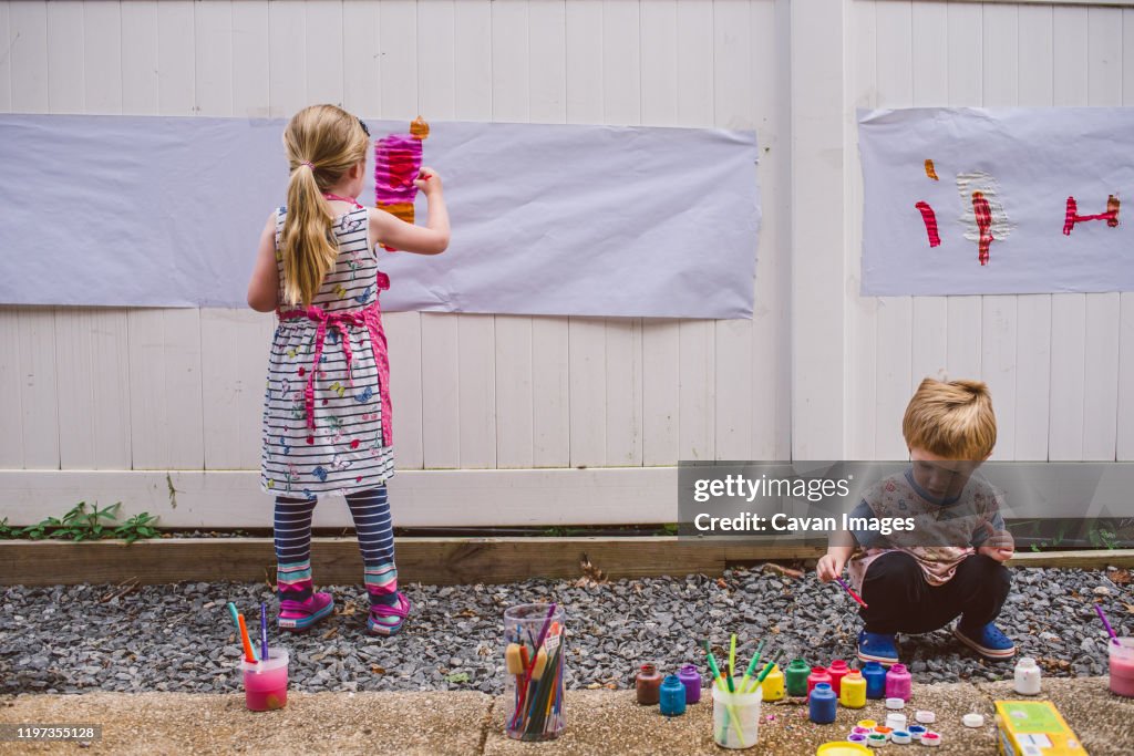 Two children paint outside.