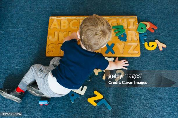 a little boy plays with an alphabet puzzle. - montessori education stock-fotos und bilder