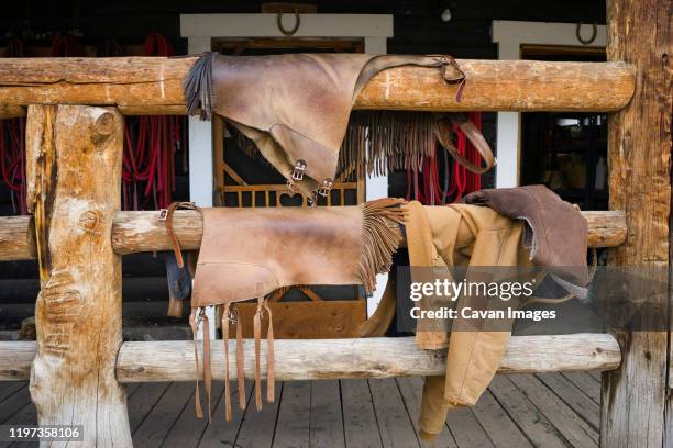 leather chaps hang on a wood porch railing after horseback riding - leather cowboy chaps fotografías e imágenes de stock