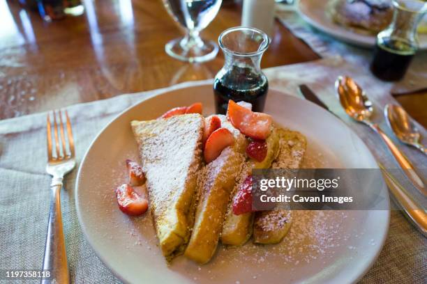 french toast with strawberries, powdered sugar and maple syrup - pain perdu stock pictures, royalty-free photos & images