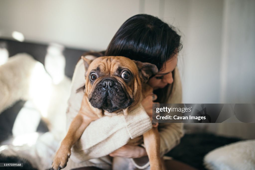A tattooed woman hugging her cute puppy. Happy moment between pe