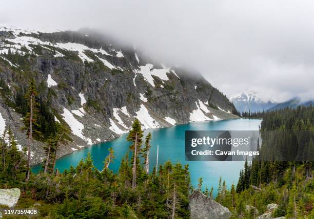 a beautiful alpine lake on a cloudy, rainy summer day in the coast mountains around pemberton, british columbia. - temperate climate stock pictures, royalty-free photos & images