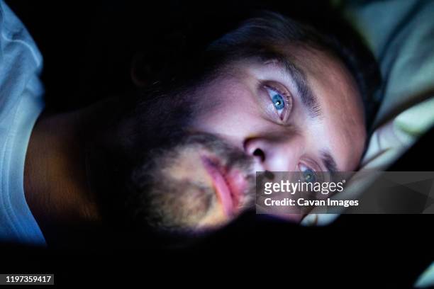 bearded caucasian male is watching something on his mobile phone - face eyes closed stock pictures, royalty-free photos & images