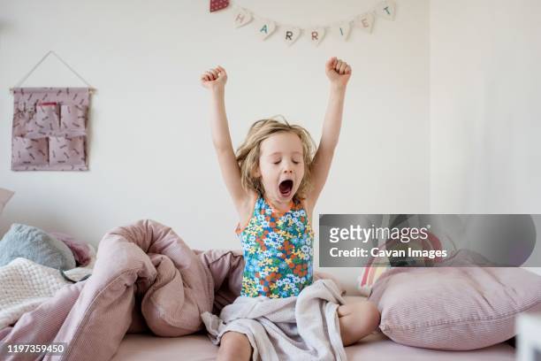 young girl waking up stretching in the morning in her bedroom at home - morning bed stretch stock-fotos und bilder