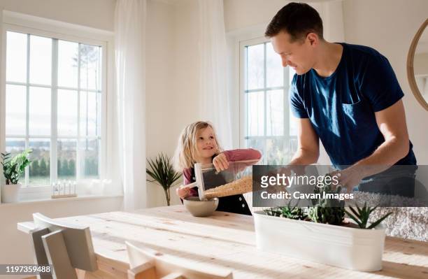 father helping his daughter make her breakfast in the morning at home - breakfast fathers imagens e fotografias de stock