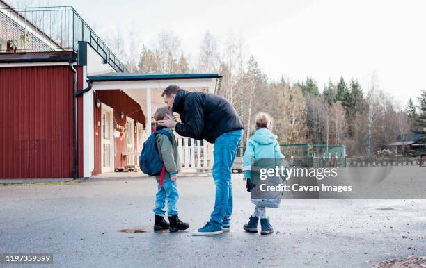 father kissing his kids goodbye at the school gates - standing apart stock pictures, royalty-free photos & images