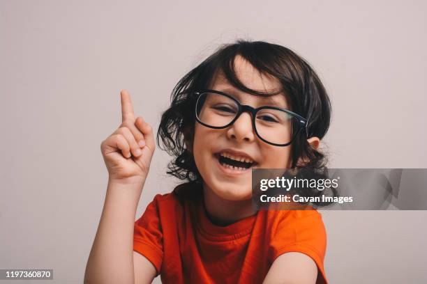 smiling little boy raising his hand - raised finger stock-fotos und bilder