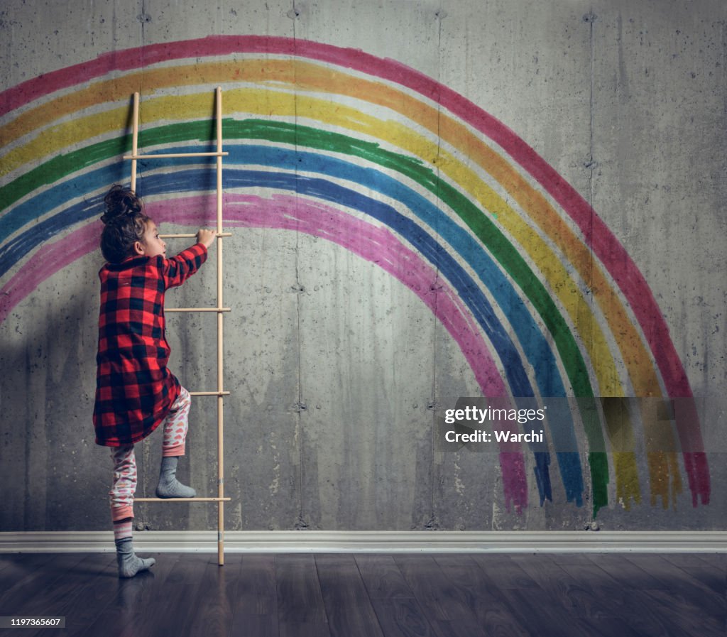 Girl climbing to reach the rainbow