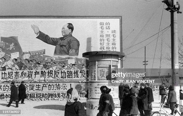 Small group of Beijing residents walk in February 1967 in downtown Beijing, past a huge poster showing the Chairman Mao Zedong, during the "Great...