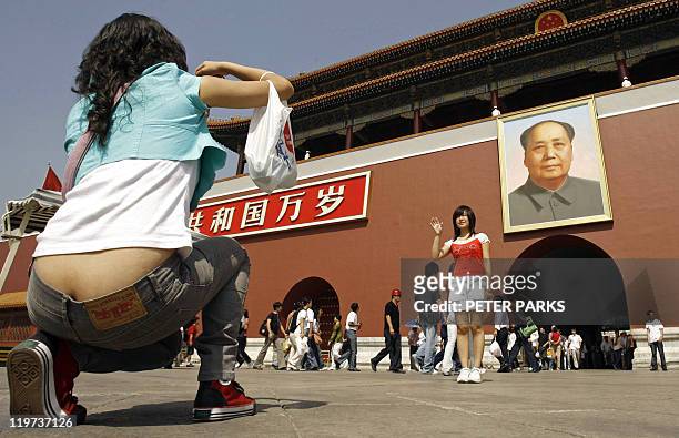 Visitors to Tiananmen Gate take their picture under the giant portrait of the late Communist Party leader Mao Zedong, 06 September 2006. Mao, who...