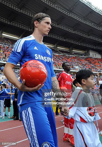 English Premier League team Chelsea player Fernando Torres walks with a Thai child ahead of a football friendly match at Rajamangala stadium in...